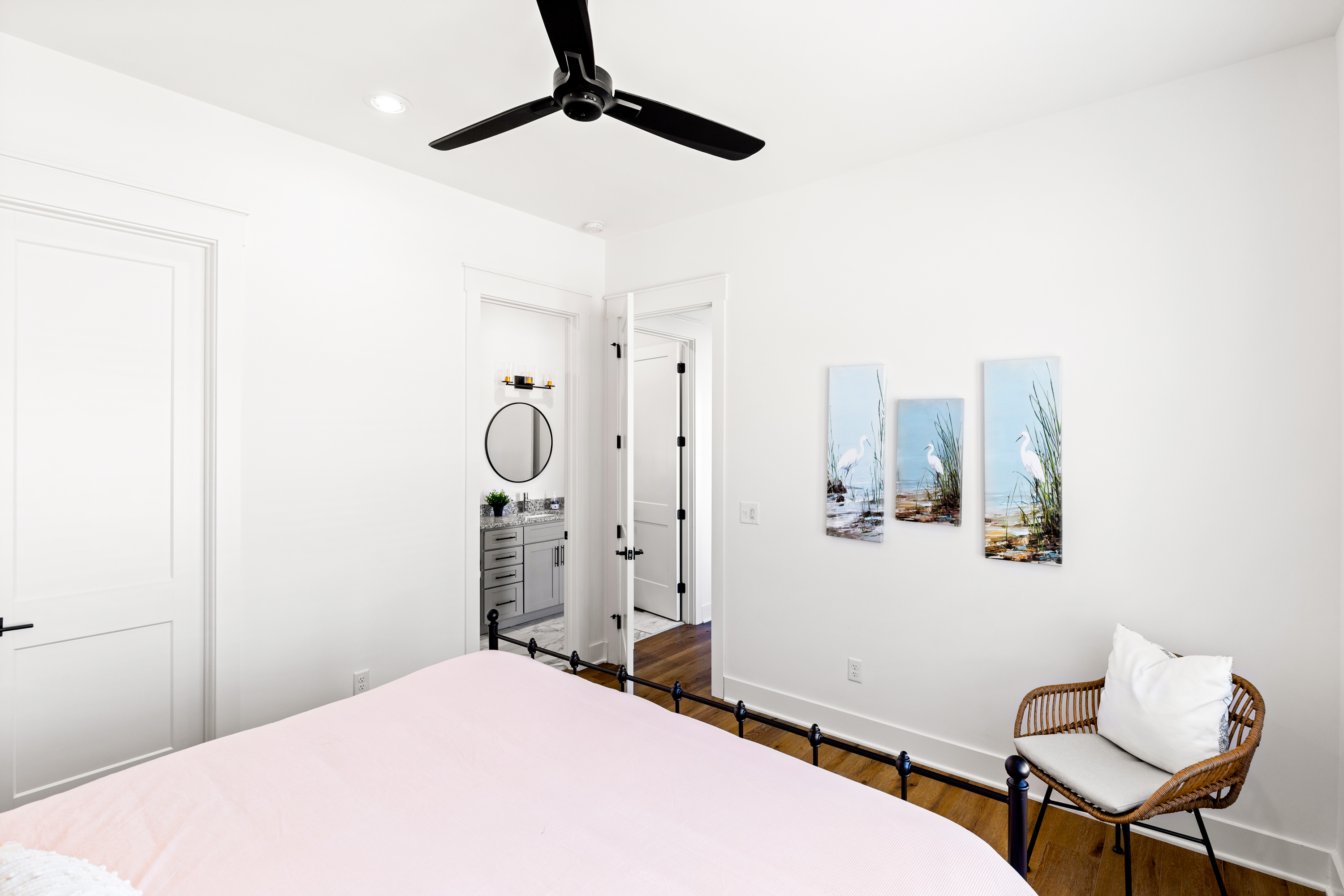 Bedroom with a pink bedspread, modern artwork, and natural lighting